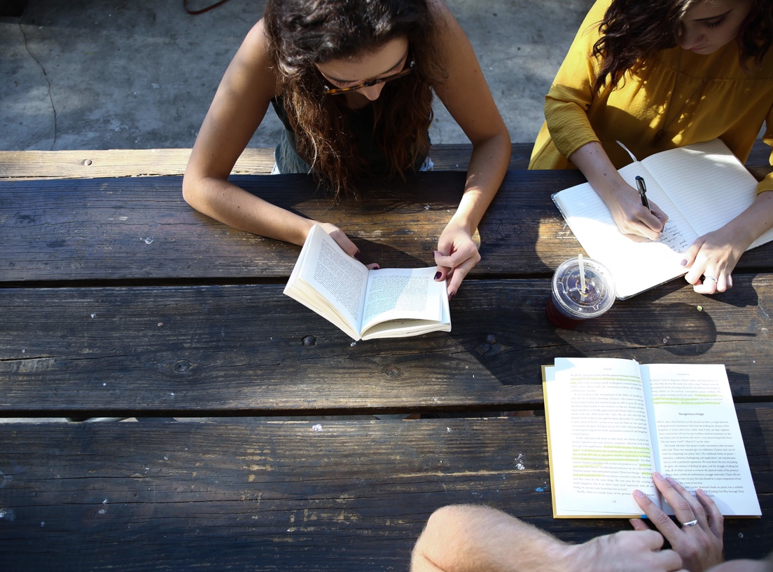 Girls studying on a rustic table usign books, notebooks and pen
