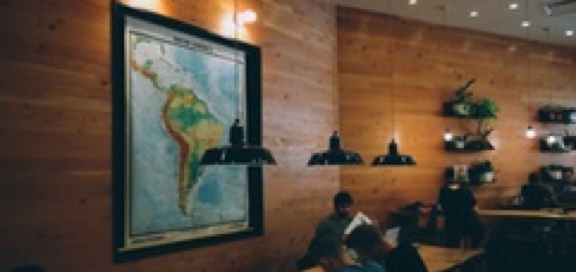 Inside a restaurant people gathering in different tables and a map of South America is placed on the wall