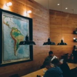 Inside a restaurant people gathering in different tables and a map of South America is placed on the wall